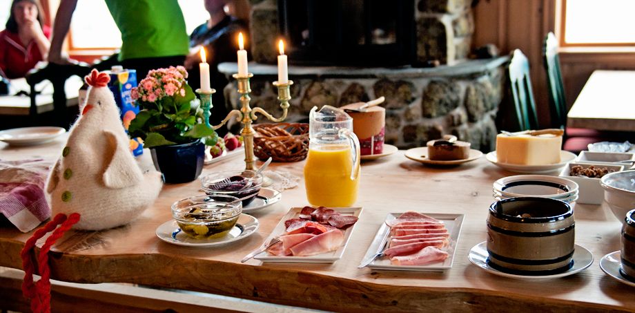 Frokostbord med stearinlys, en påskekylling, appelsinjuice og forskjellig pålegg.