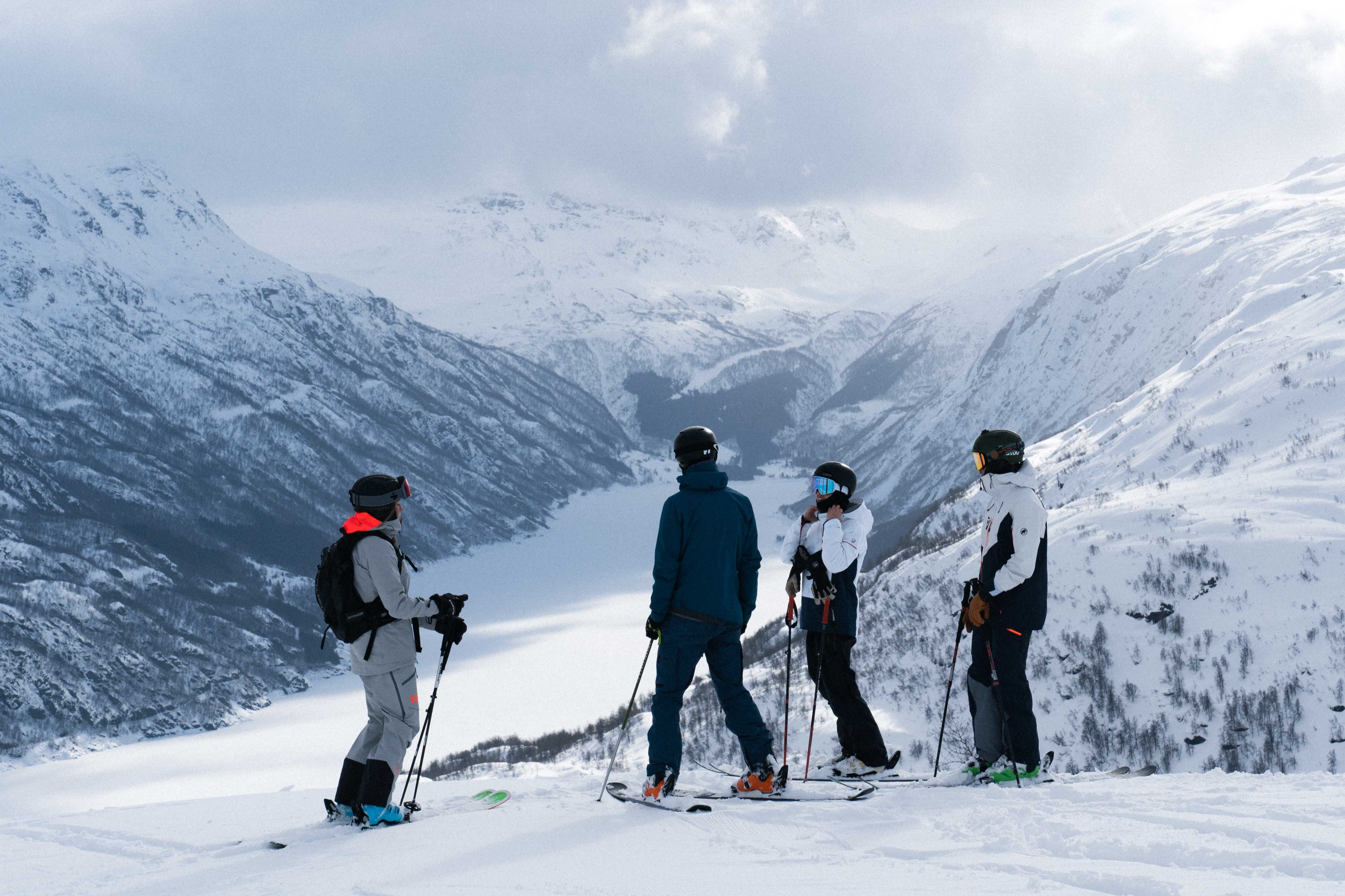 Fire personer på slalomski i et vakkert vinterlandskap.
