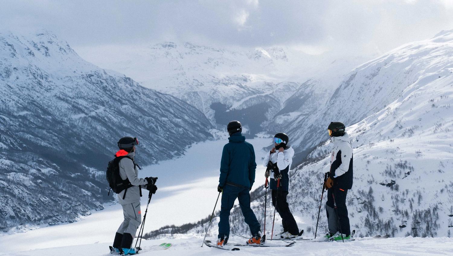 Fire personer på slalomski i et vakkert vinterlandskap.