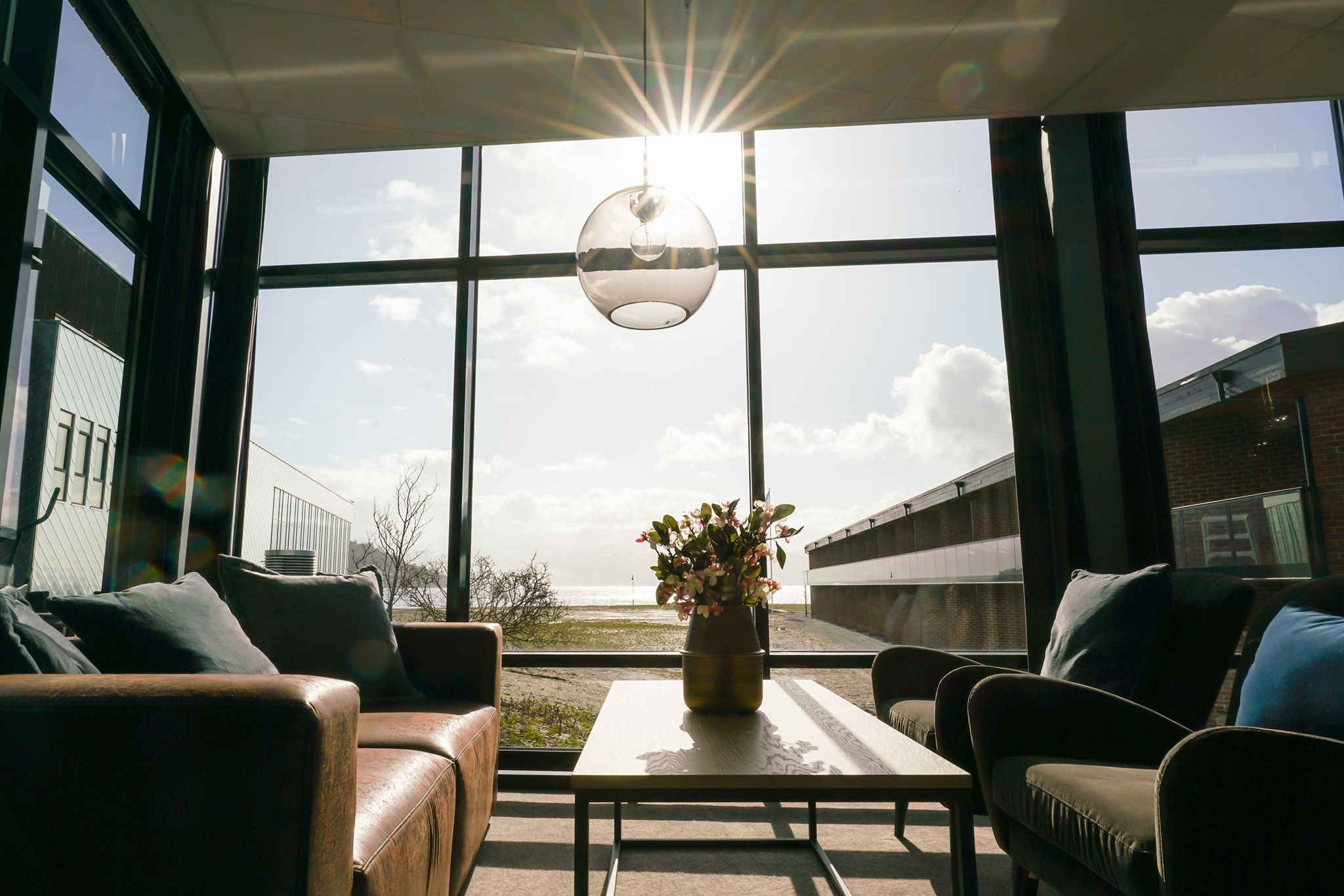 Lys og moderne lounge med store vindauge og solstrålar som skin inn.