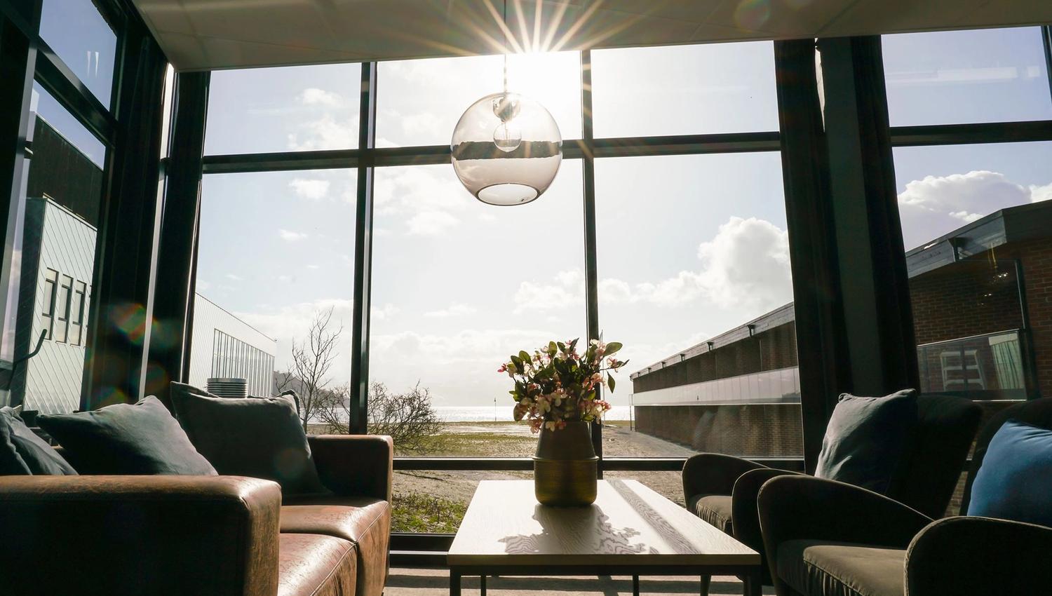 Lys og moderne lounge med store vindauge og solstrålar som skin inn.