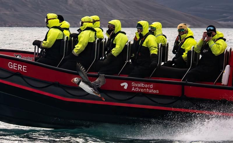 Turgrupper i gule drakter på RIB-båt i høy fart.
