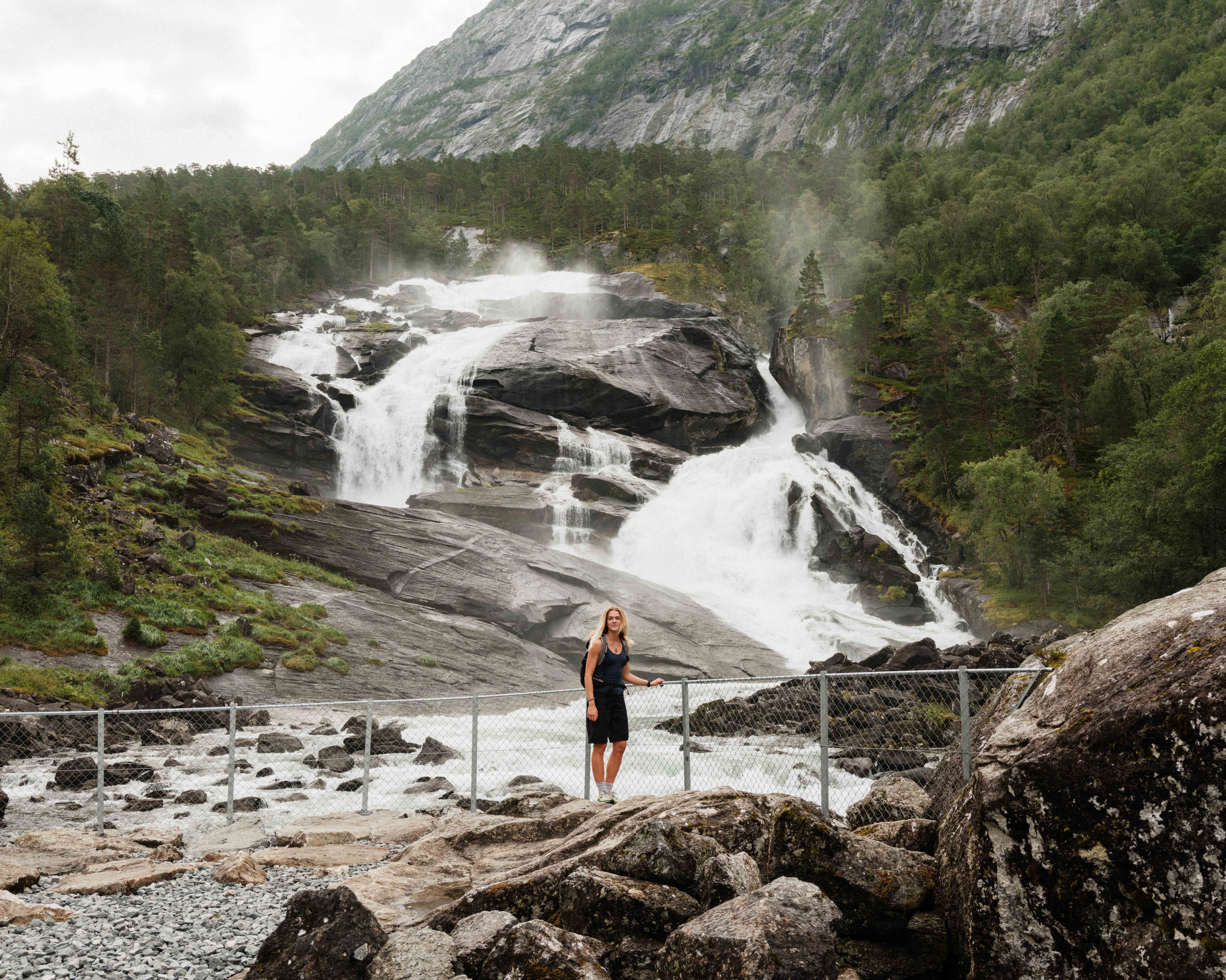 Kvinne ved elvekanten nedanfor Tveitafossen – den første fossen på fotturen gjennom Husedalen.