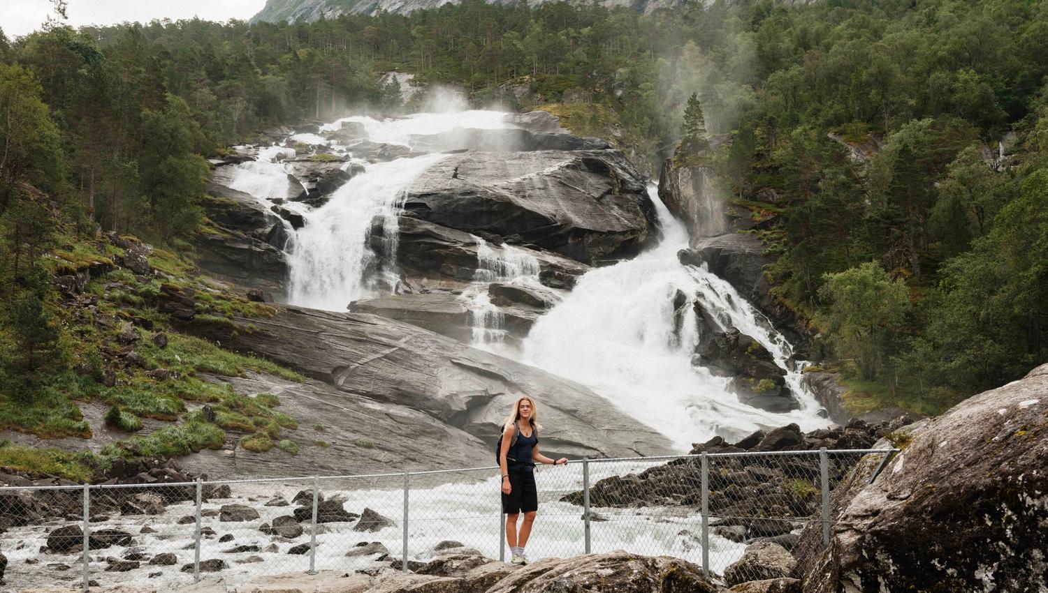 Kvinne ved elvekanten nedanfor Tveitafossen – den første fossen på fotturen gjennom Husedalen.