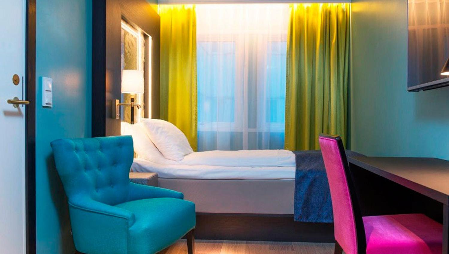 room with bed, armchair and desk in bright colours