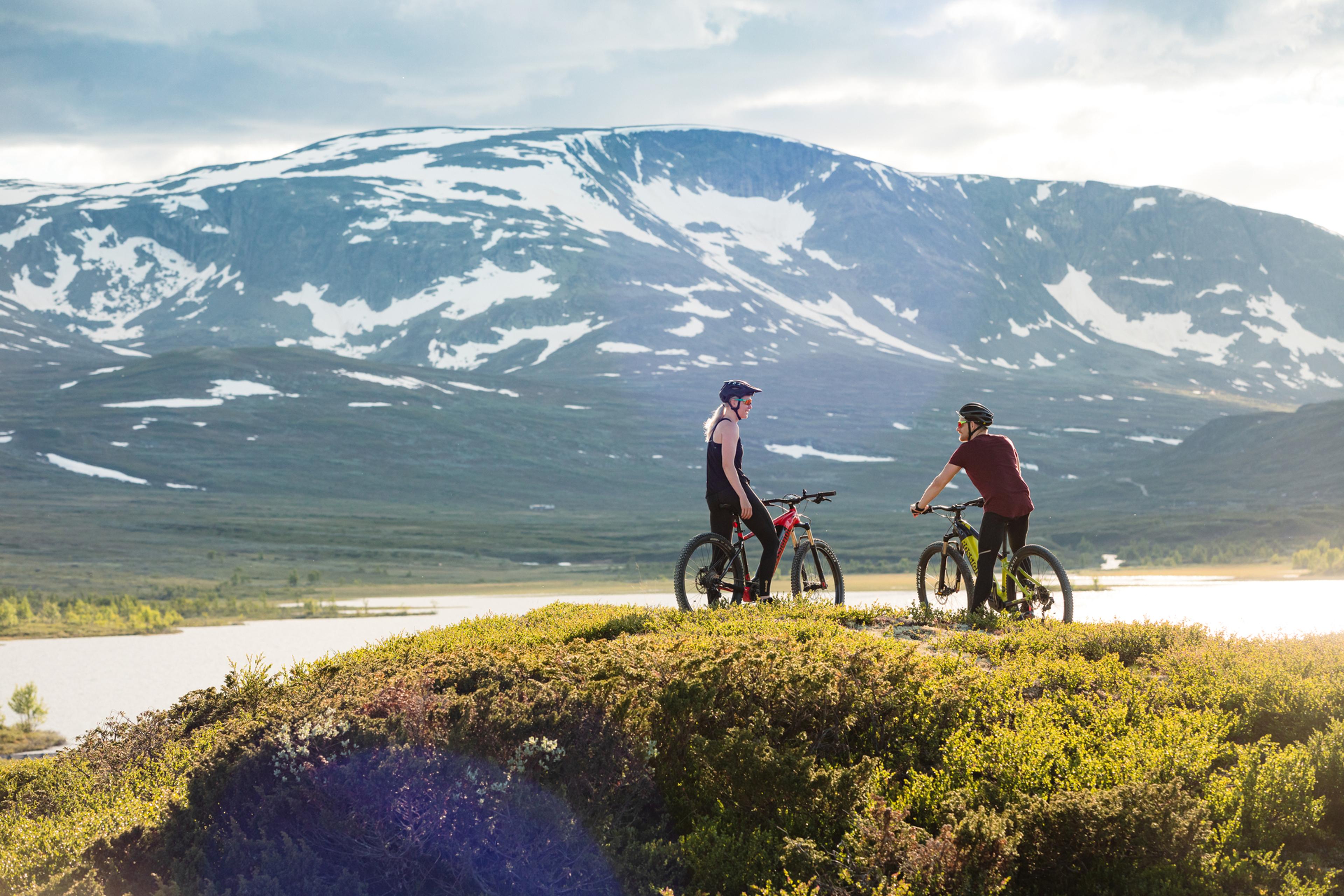 To syklister som slapper av foran Budalsvatnet i mektig Hallingskarvet nasjonalpark.