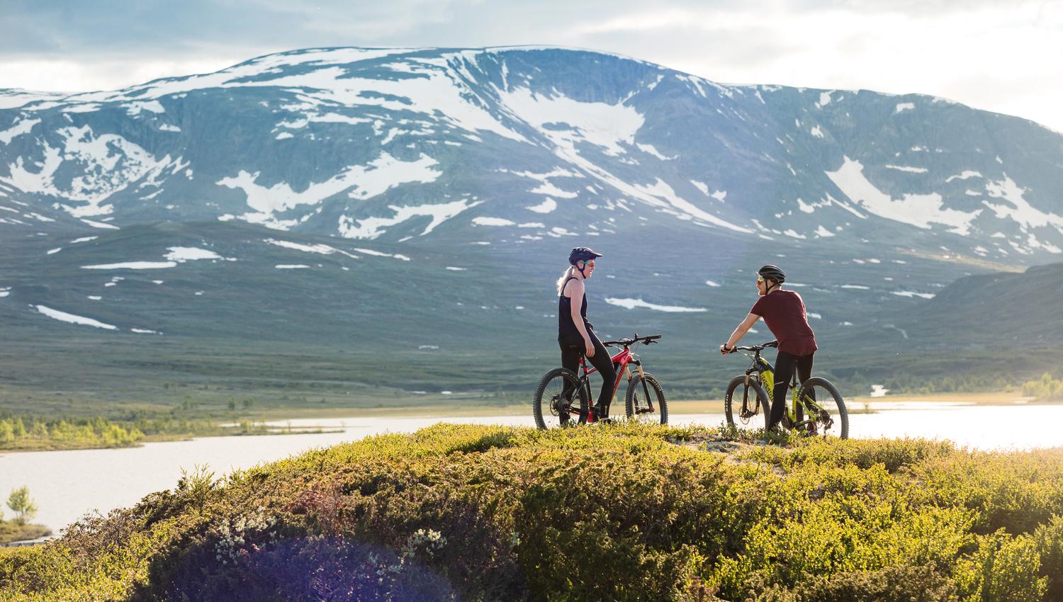 To syklister som slapper av foran Budalsvatnet i mektig Hallingskarvet nasjonalpark.