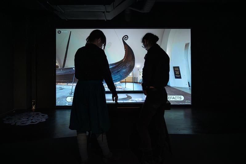Two people interacting with the digital exhibition from The Viking Ship Museum