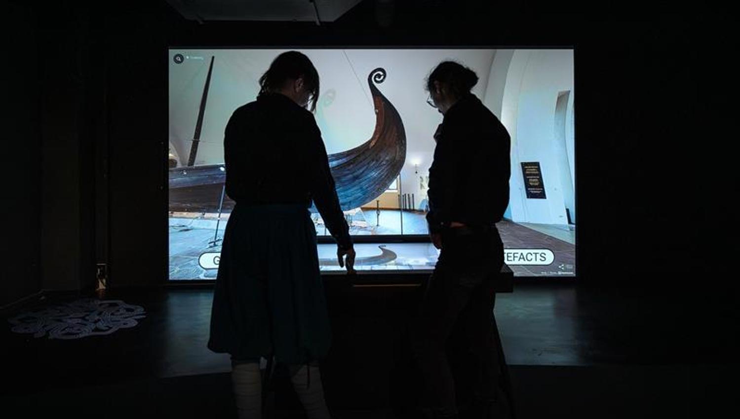 Two people interacting with the digital exhibition from The Viking Ship Museum