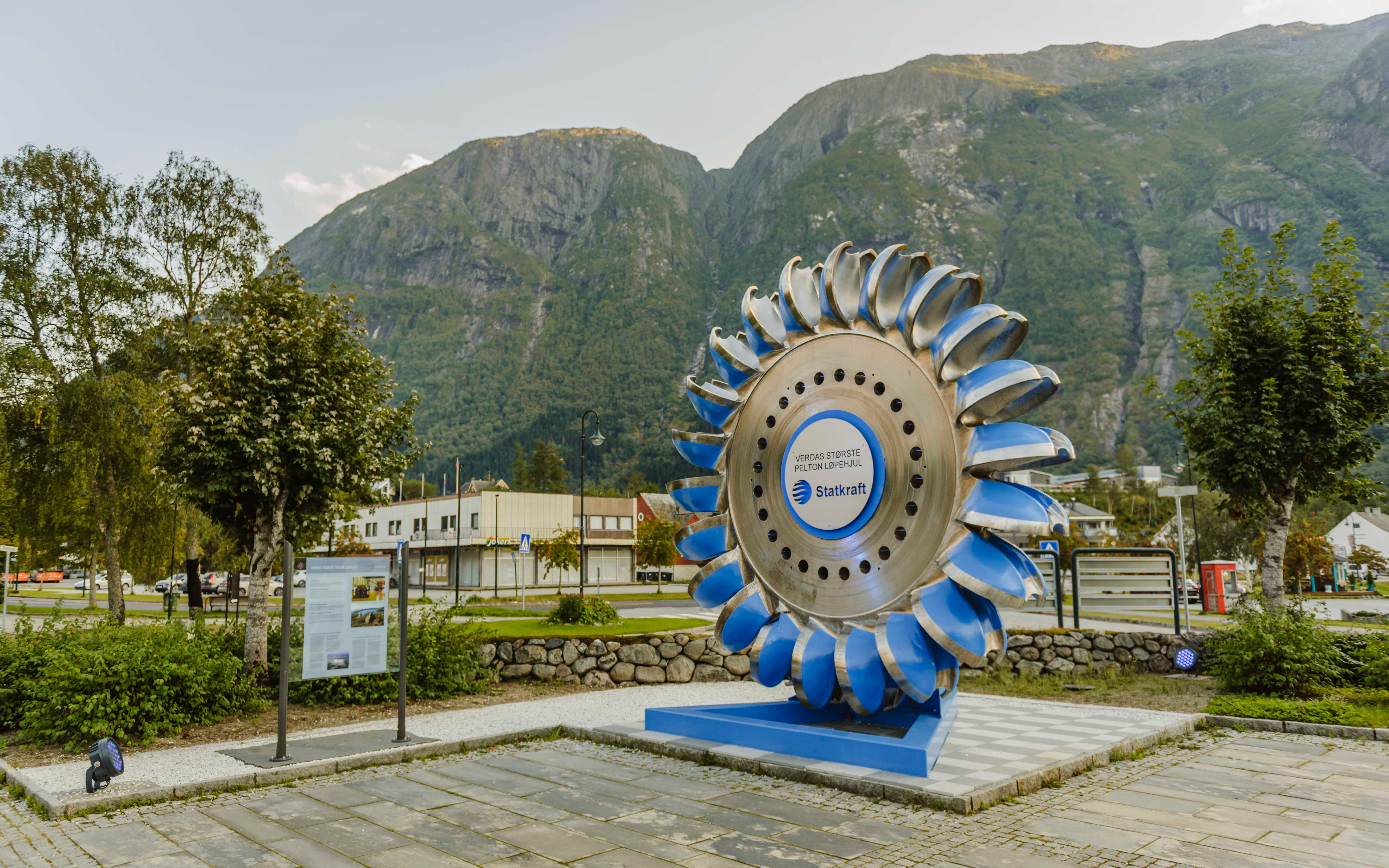 A large, blue pelton wheel from Statkraft on display in the park.