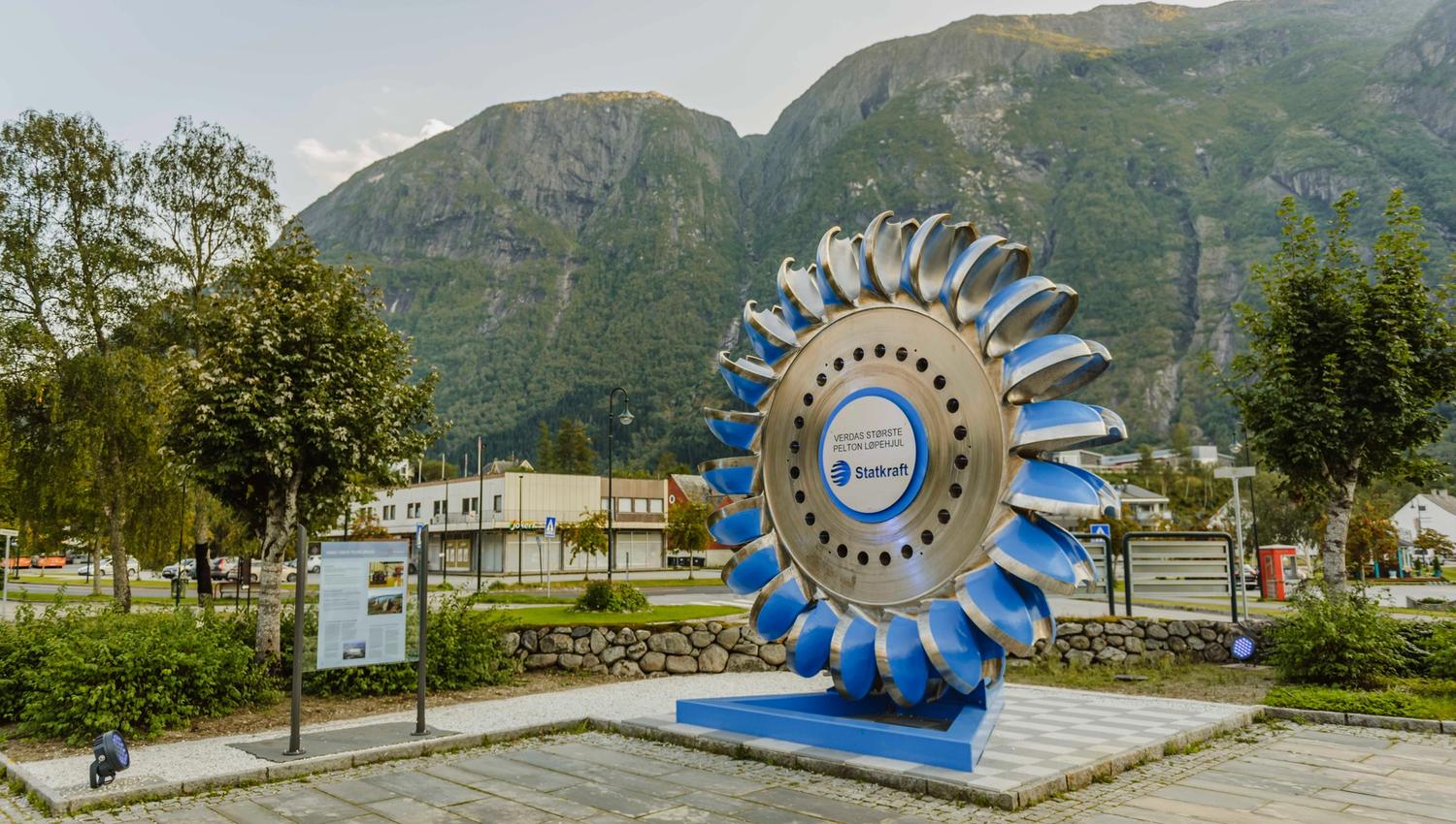 A large, blue pelton wheel from Statkraft on display in the park.