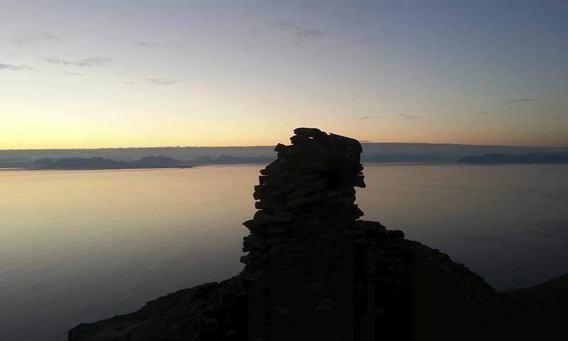 The cairn on top of Fuglefjella in sillhouette against the fjord Isfjorden in dusk light conditions