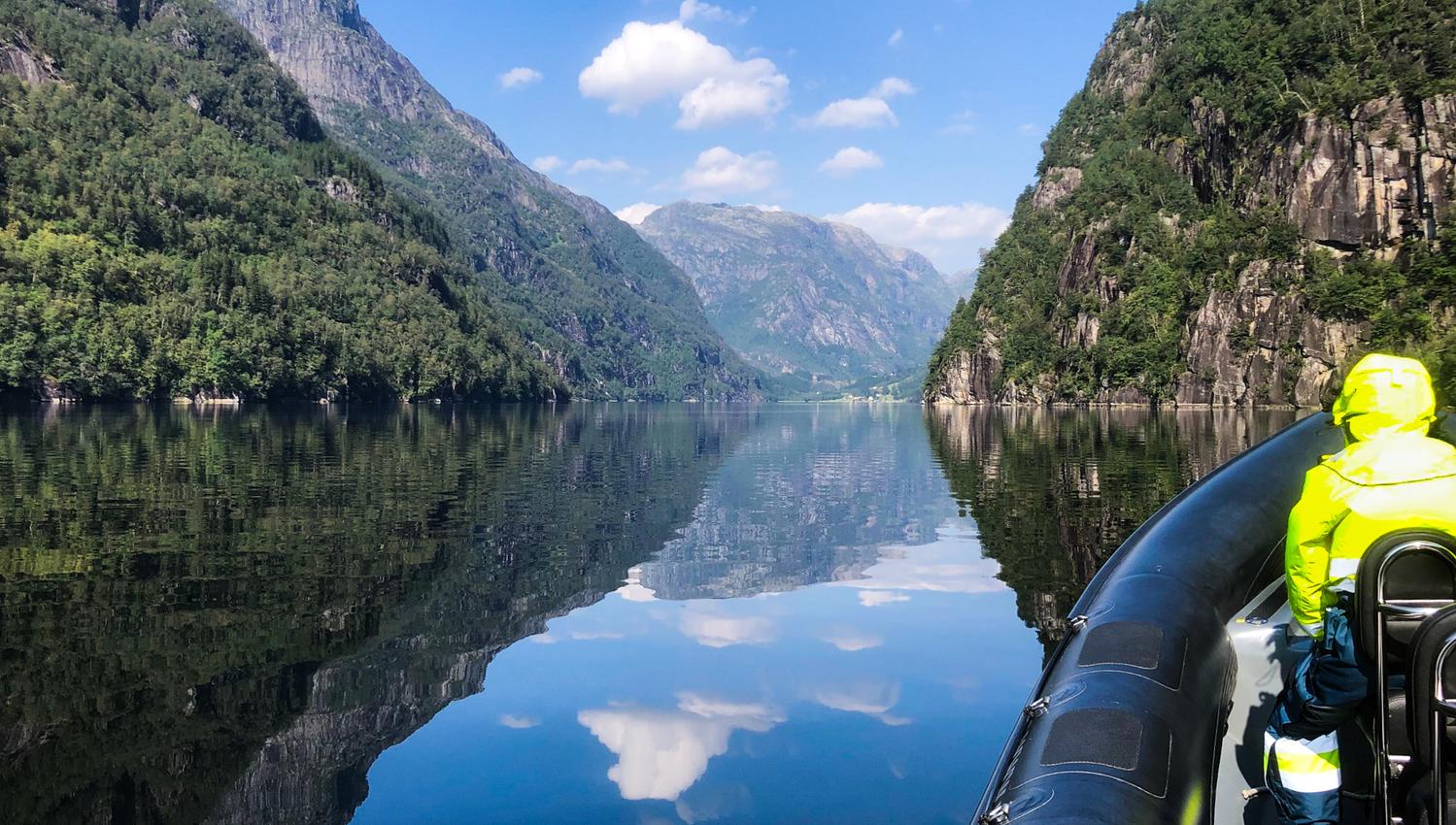 Spegelblank fjord omgitt av majestetiske fjell, sett frå ein RIB-båt på Norheimsund RIB Seafari i Hardanger.