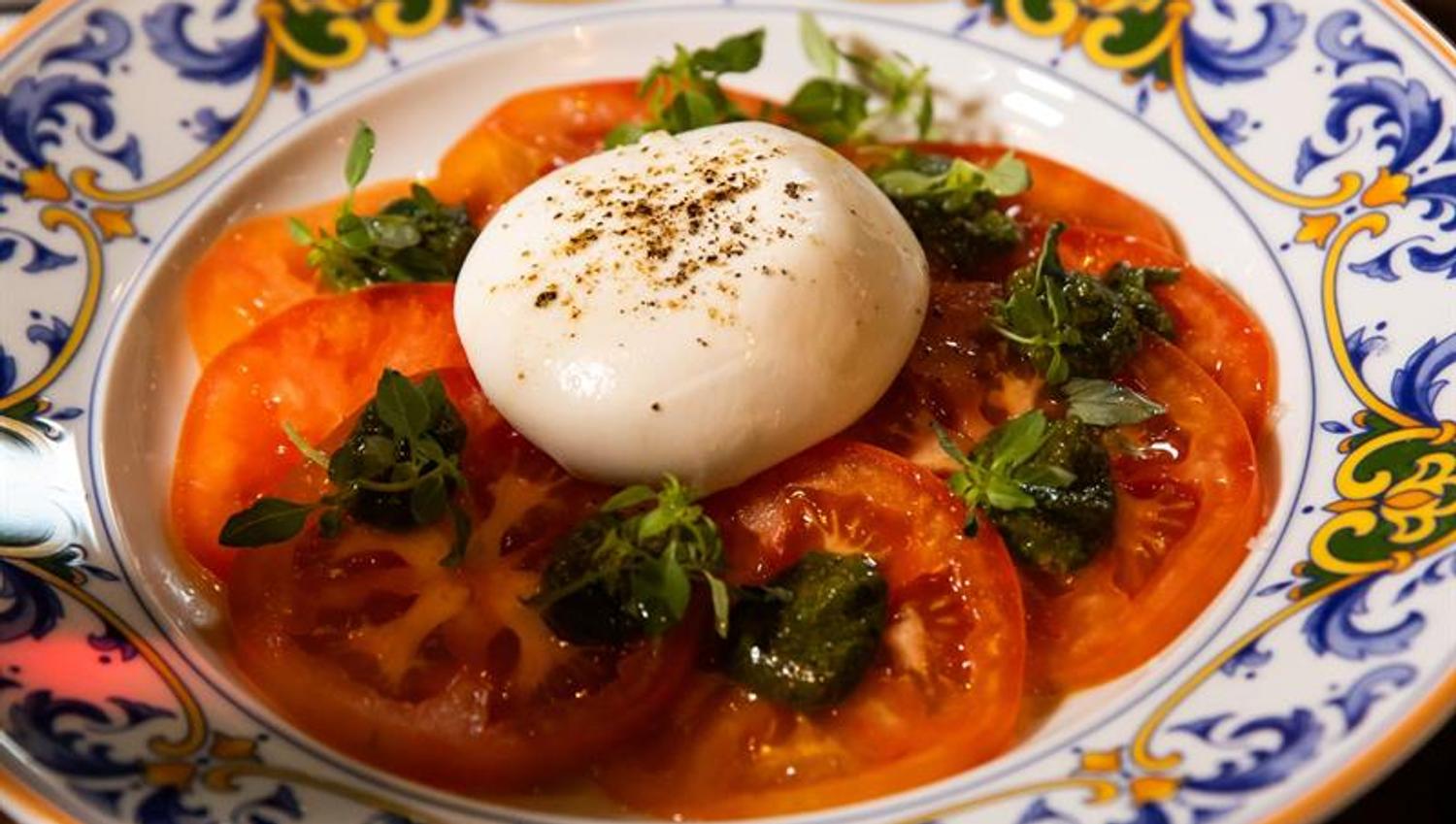 Detalj av mozarella på en seng av tomatskiver på en tallerken