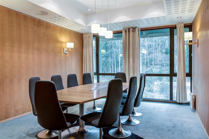 Elegant styrerom med rundt bord, komfortable stoler og utsikt mot grøntområde