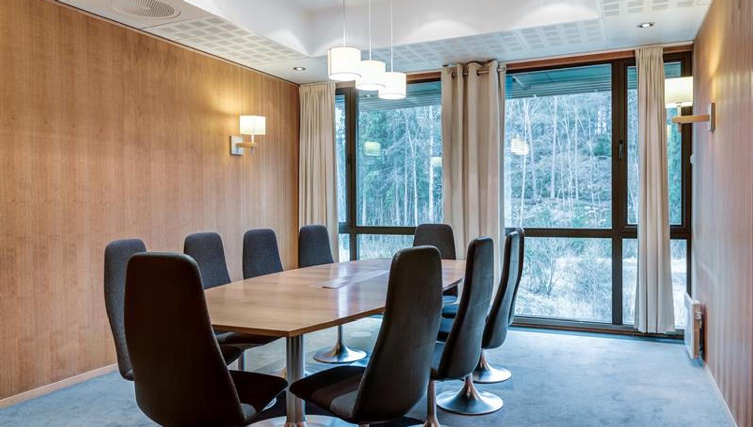 Elegant styrerom med rundt bord, komfortable stoler og utsikt mot grøntområde