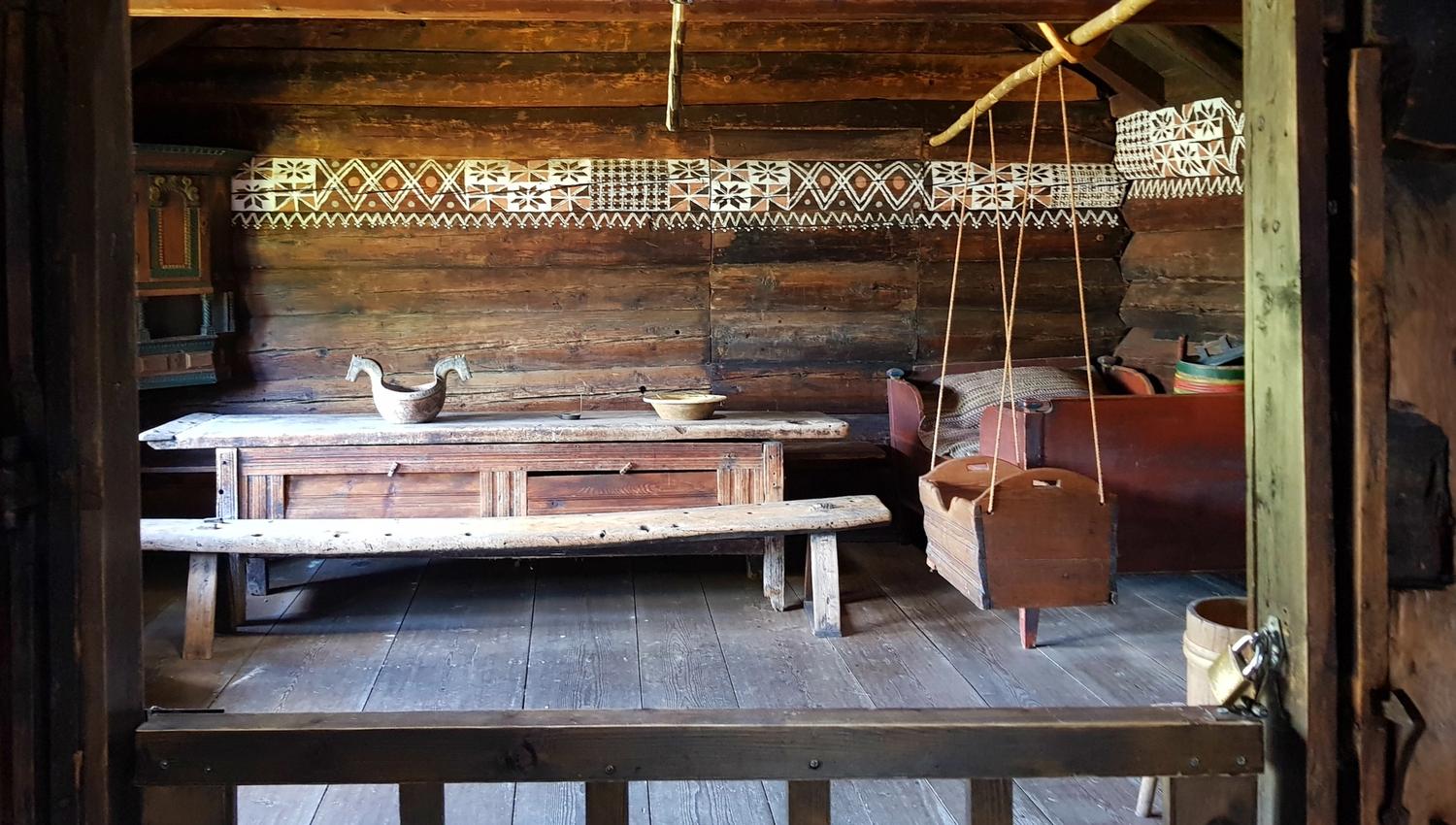Utsyn inn i ei tradisjonell stove med langbord og utskorne trekar på Hardanger folkemuseum.