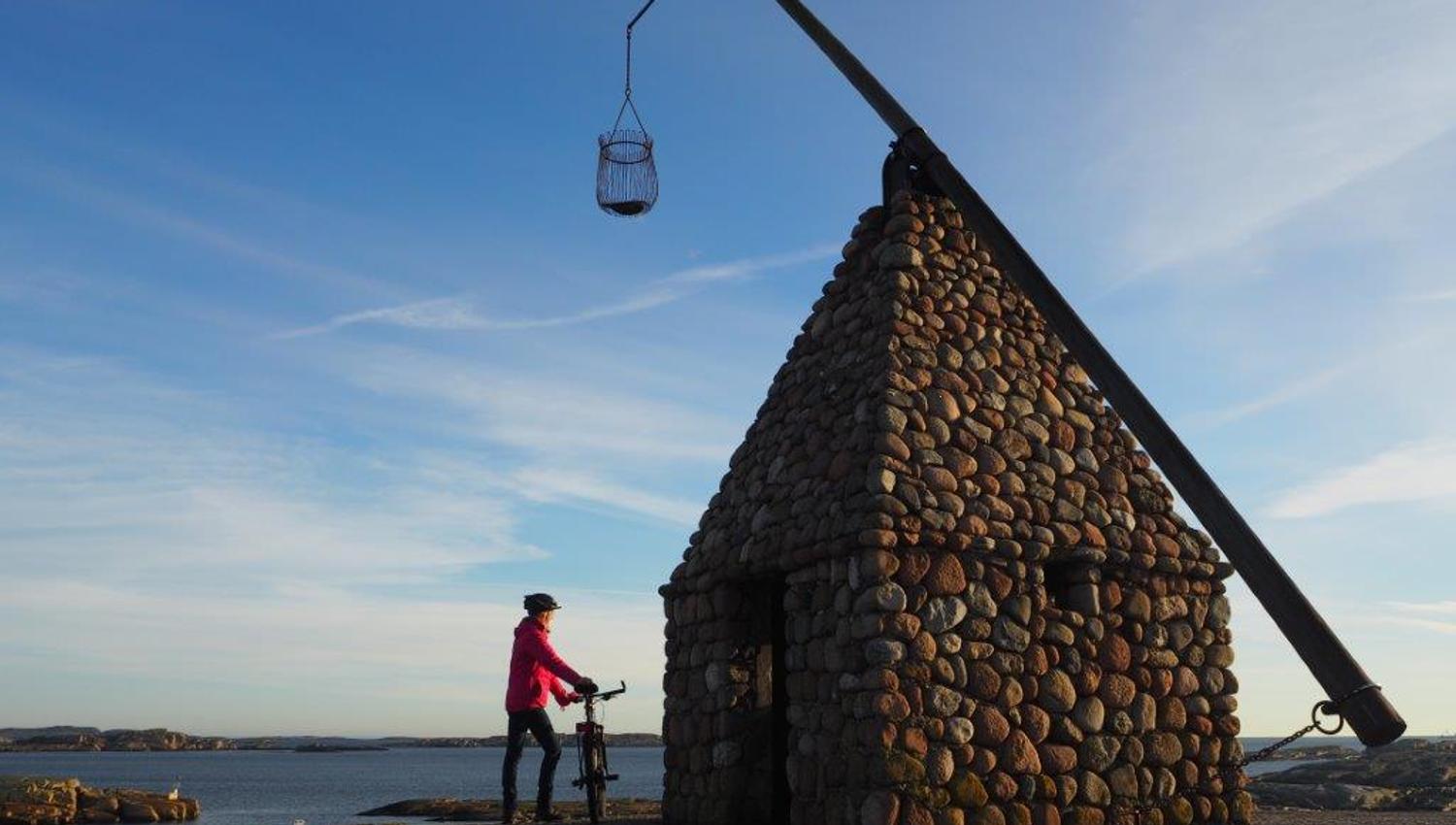 One with a bicycle by the tilting lighthouse at Verdens Ende
