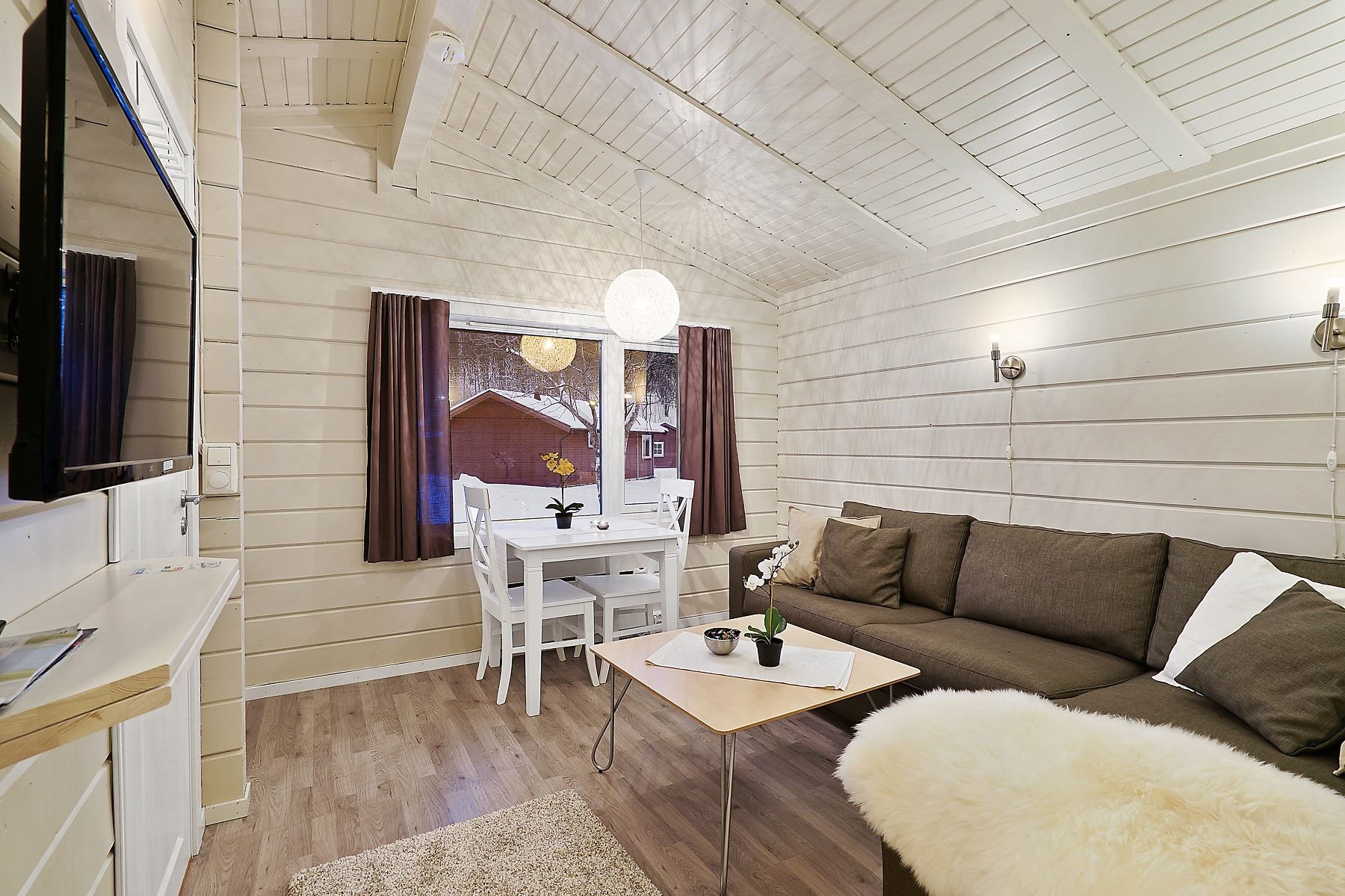 Living room with brown sofa, dining table by the window, and light wooden floors