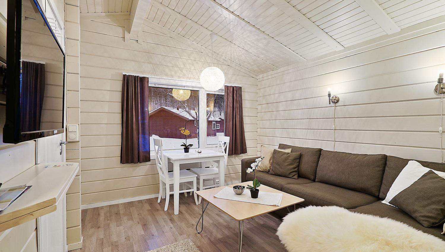 Living room with brown sofa, dining table by the window, and light wooden floors