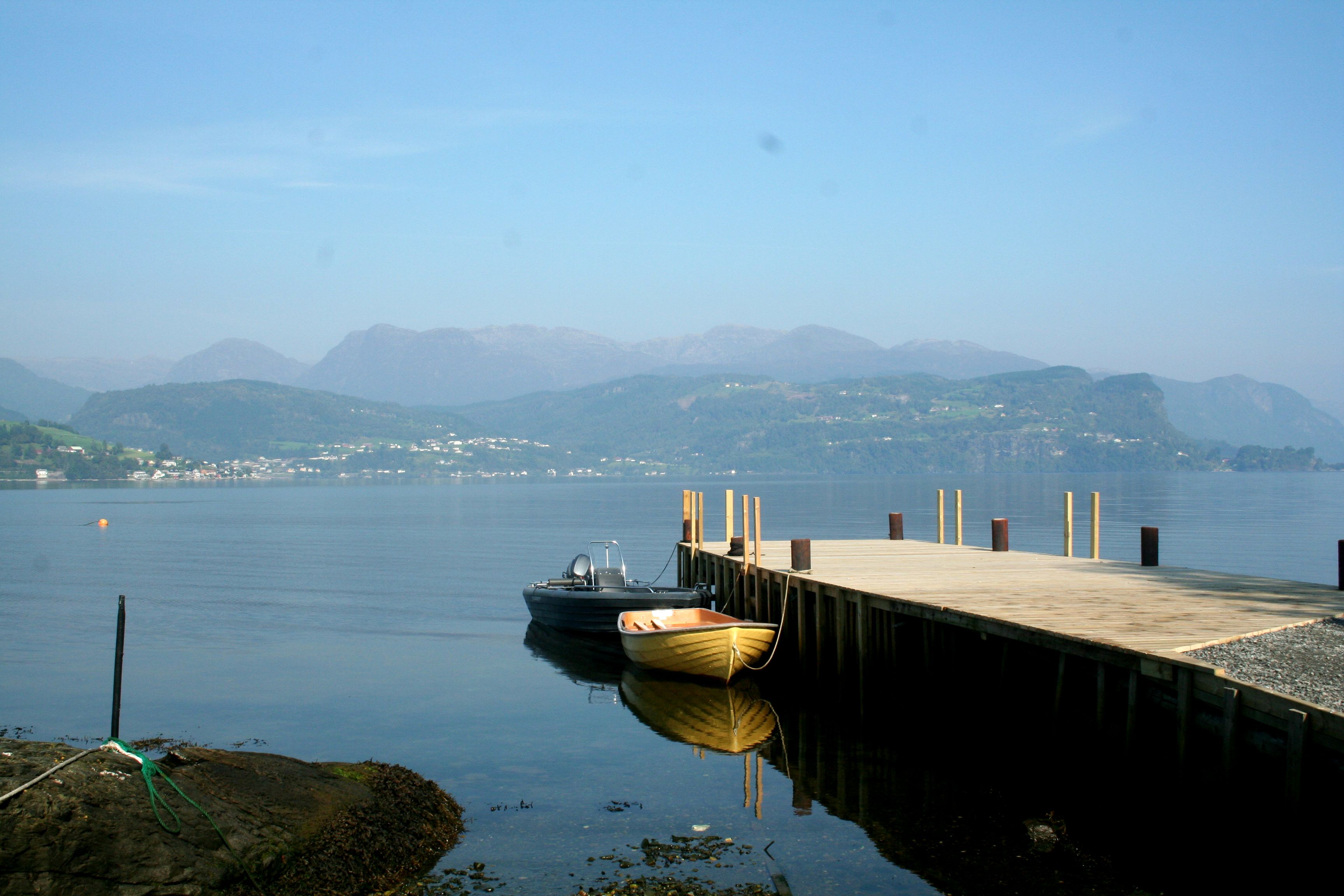 Brygge og båtar ved Oddland Camping med utsikt mot fjell og fjordlandskap i Hardanger.