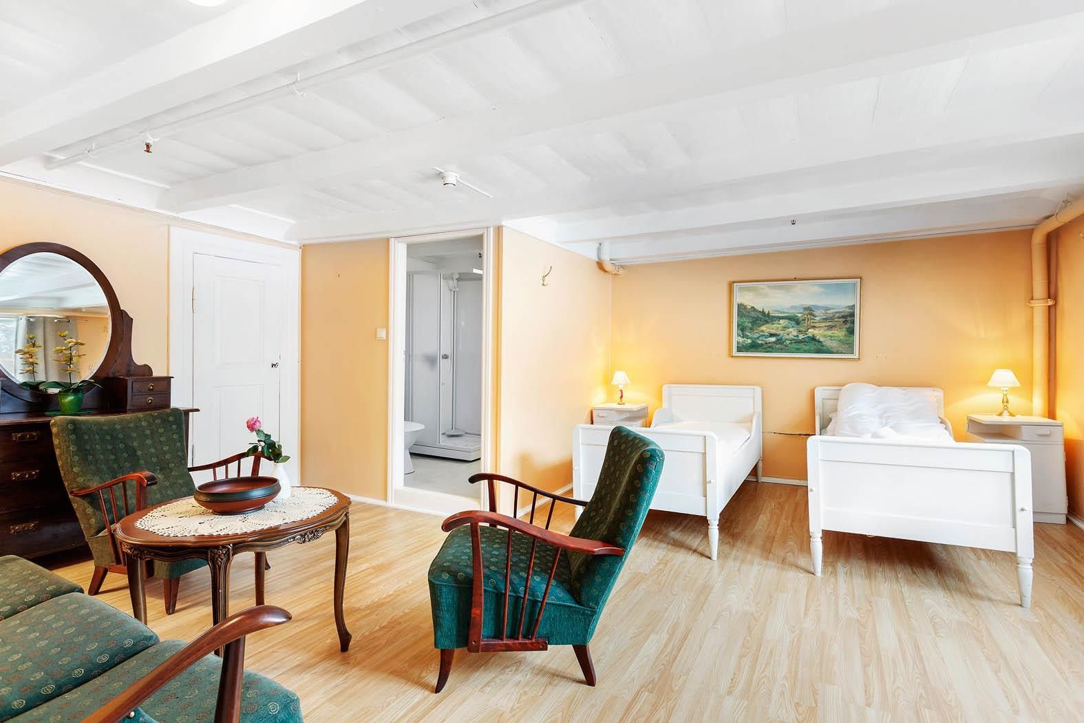 Rom med to enkle senger og sittegruppe på Jaunsen Gjestgjevarstad i Hardanger.