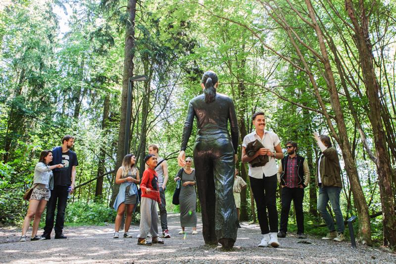 People standing in front the of the sculpture "Walking Woman".