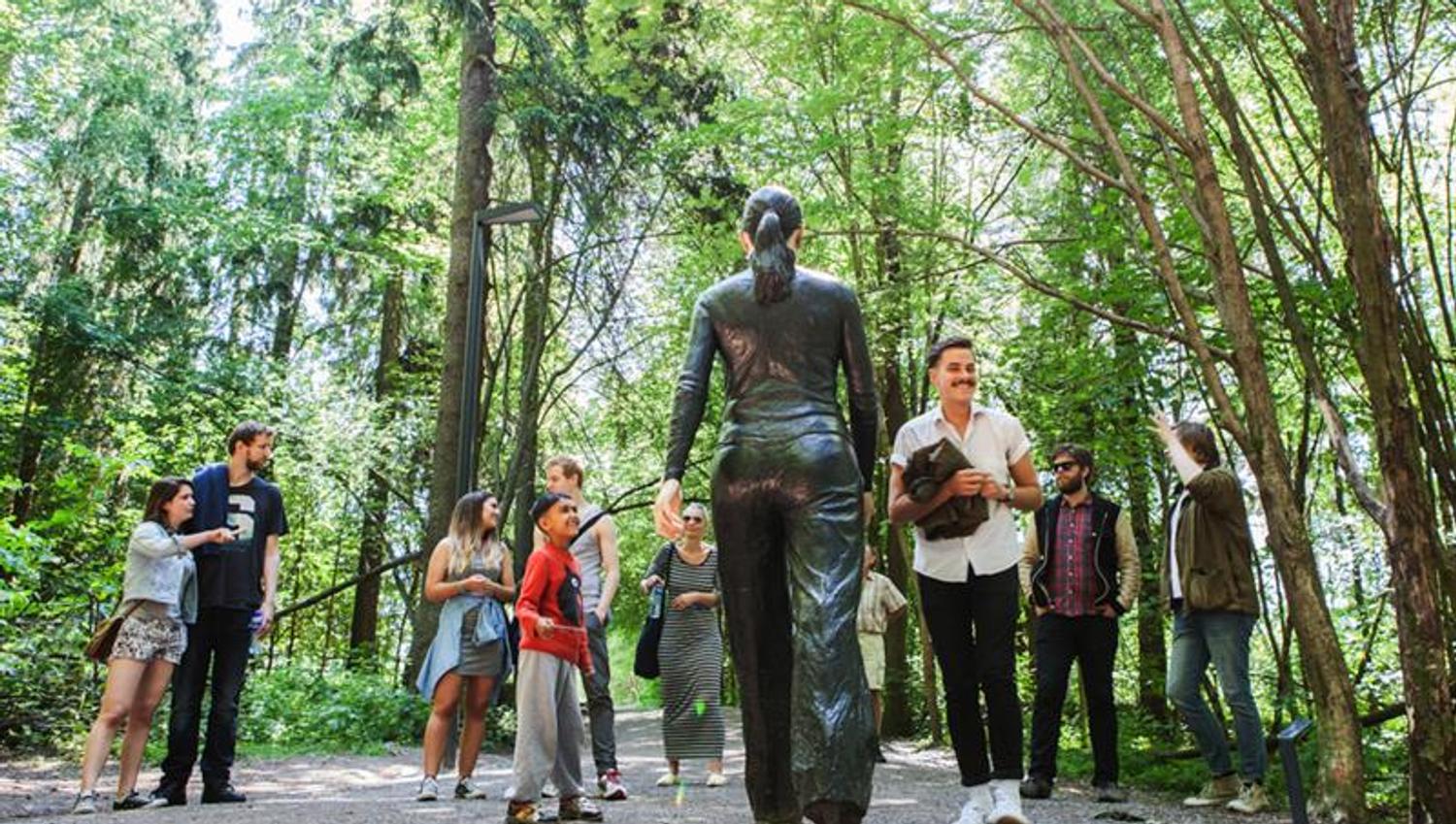 People standing in front the of the sculpture "Walking Woman".