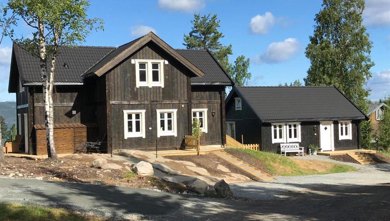 En moderne trehytte omringet av trær og natur.