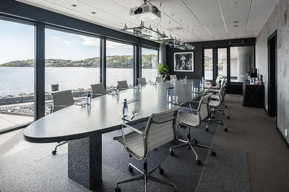 Møterom med sjøutsikt, bord og stoler.
