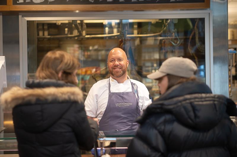 Ansatt bak disken som hjelper to kunder