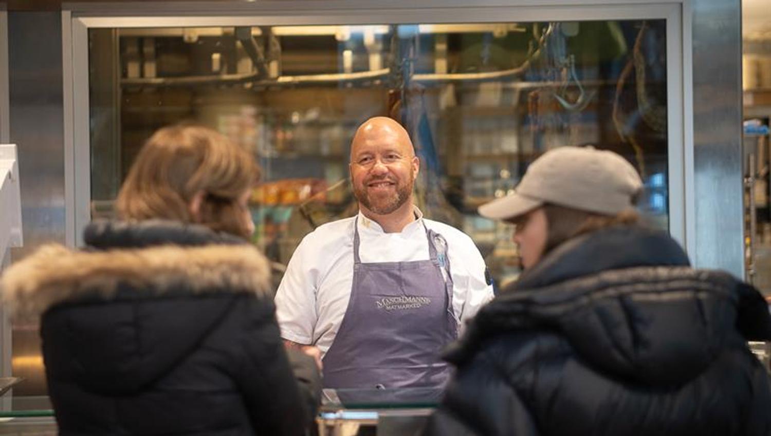 Ansatt bak disken som hjelper to kunder