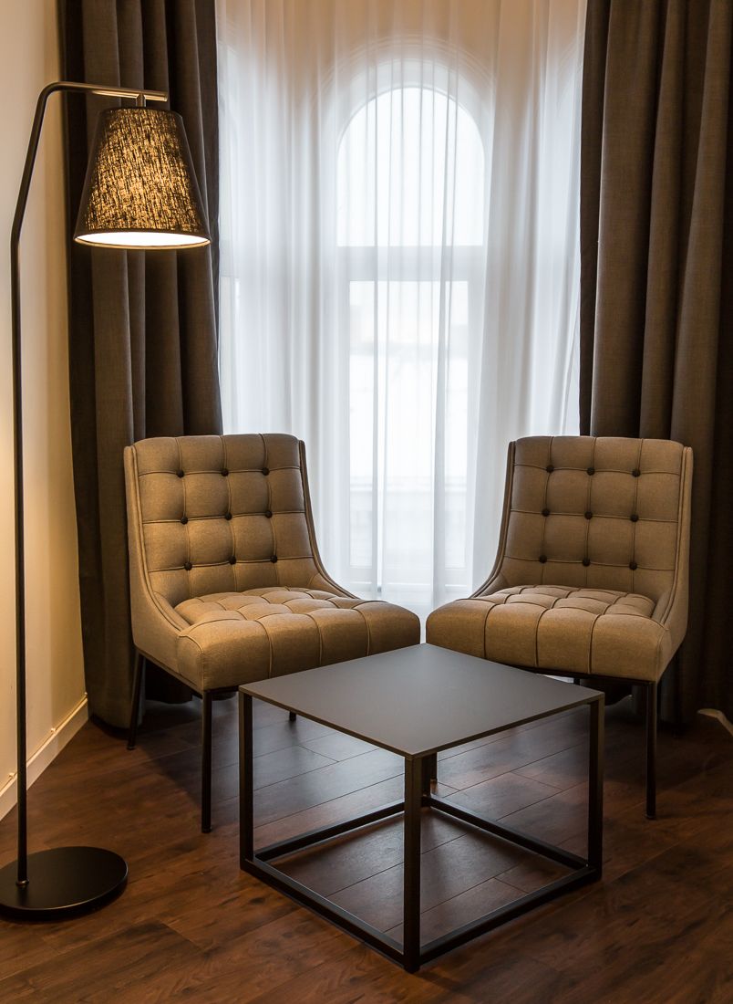 to brune stoler, kaffebord og stålampe foran vindu. Saga Hotel & Poshtel Oslo Central. Foto.