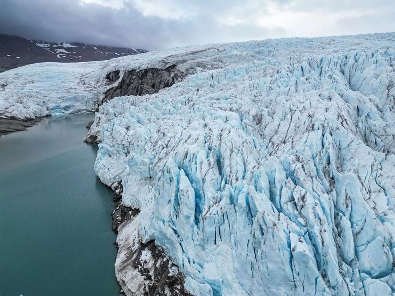 Dronebilde av blå isbre og smeltevann.