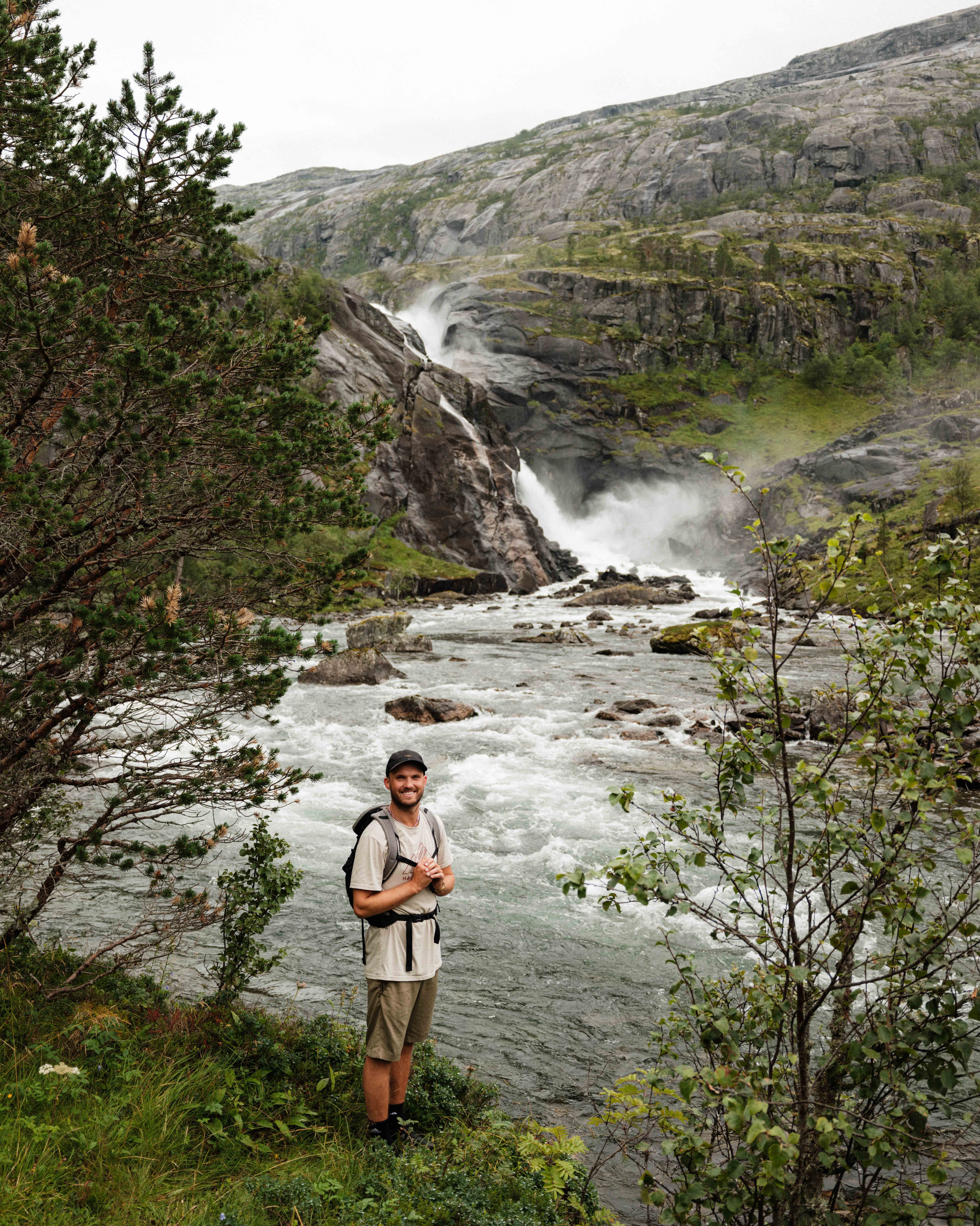 Smilande turgåar ved elva, med Nykkjesøyfossen buldrande i bakgrunnen.