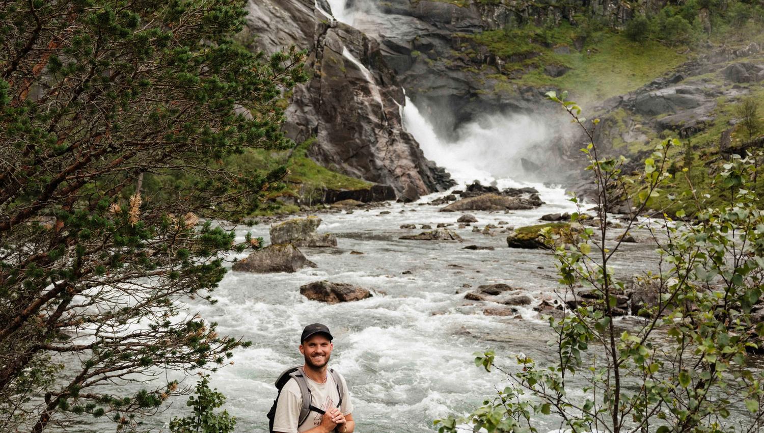 Smilande turgåar ved elva, med Nykkjesøyfossen buldrande i bakgrunnen.