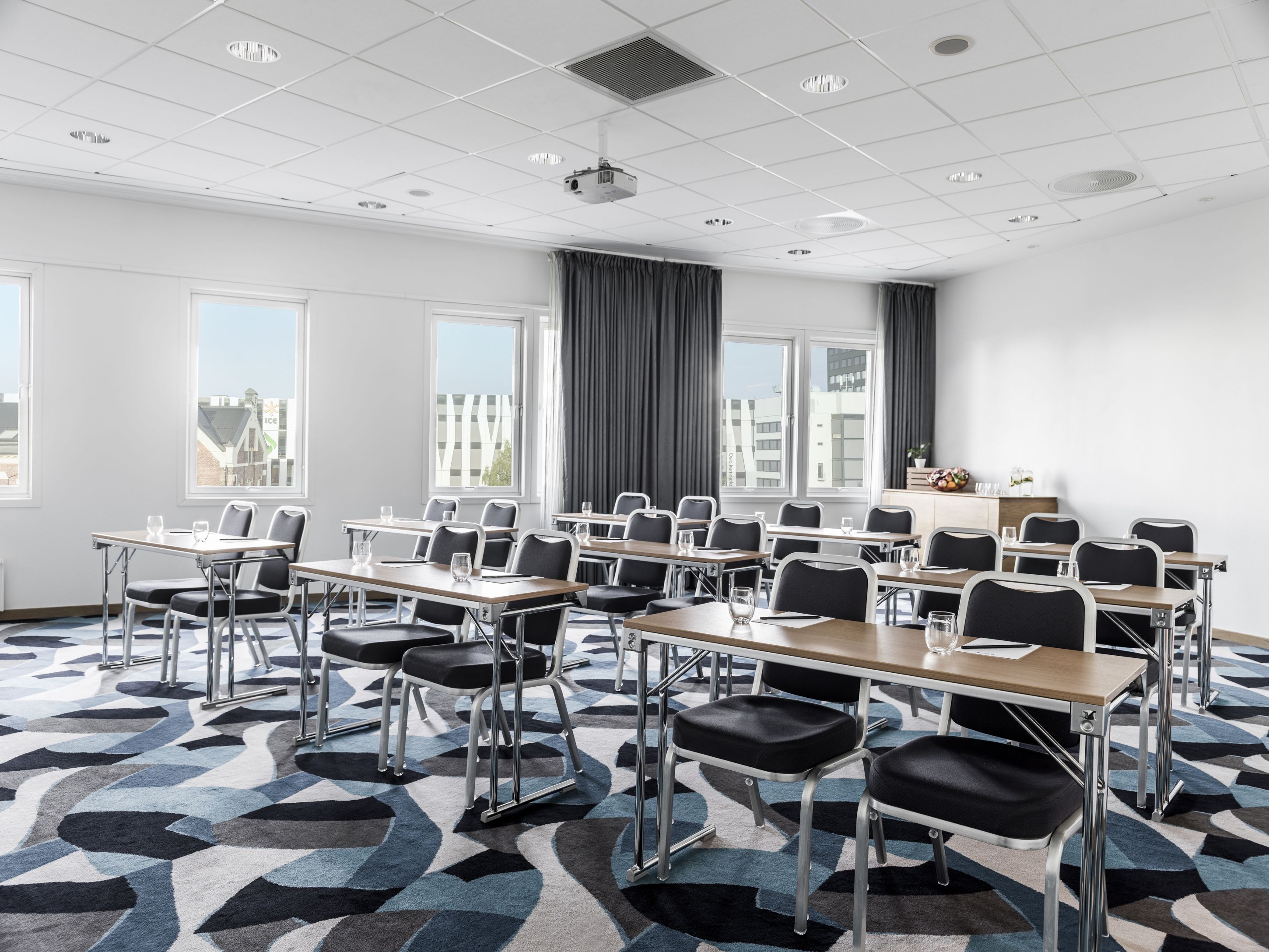 Classroom setup in a meeting room. patterned carpet, two seats per table. Photo