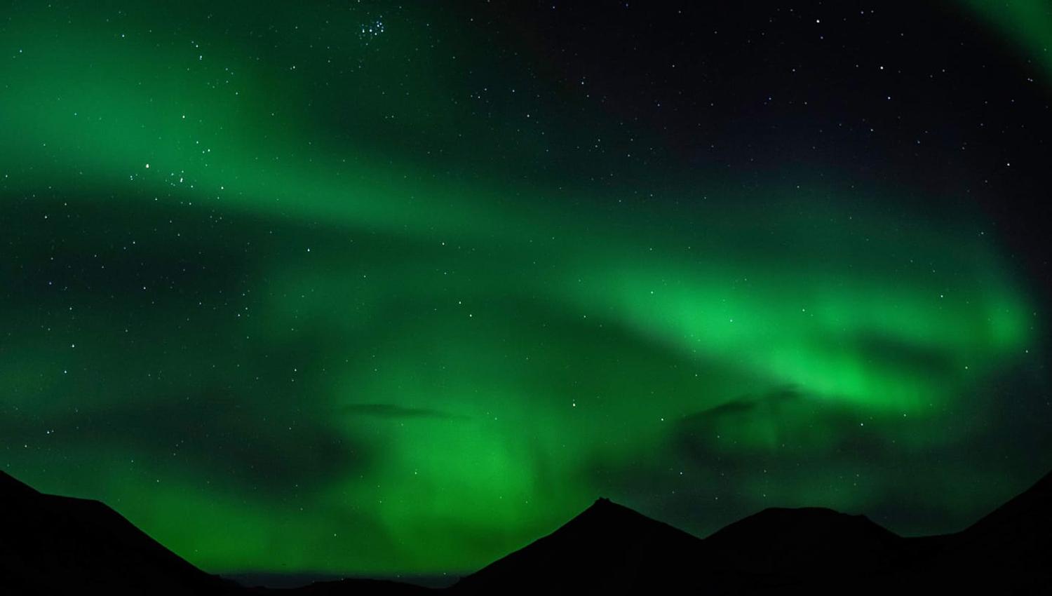 Nordlys som skinner over fjell