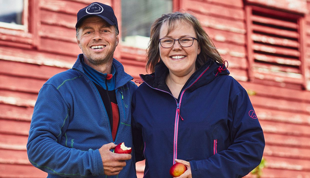 Vertskapet på Helleland Gard, smilande med friske epler frå garden.