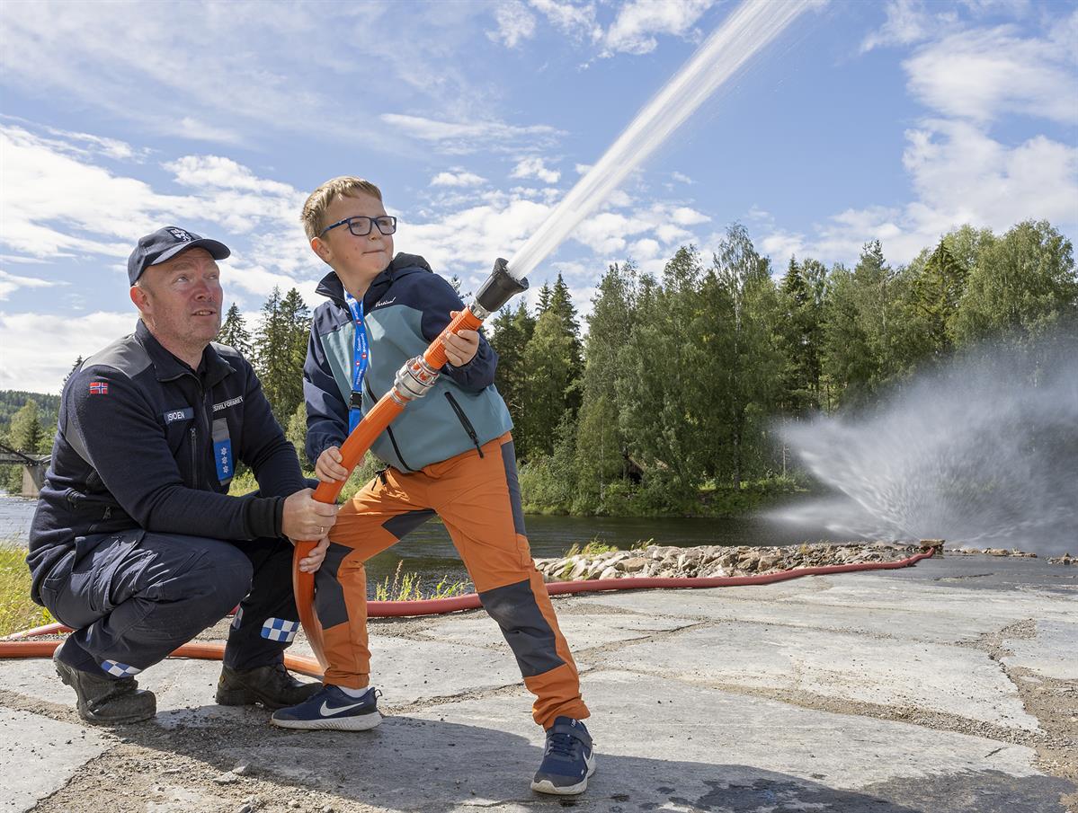Gutt får prøve brannslange under arrangement på Skogmuseet