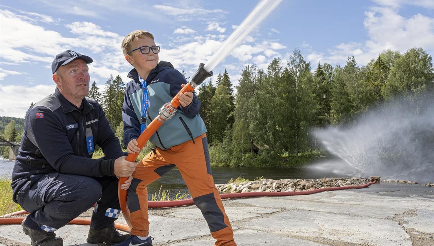 Gutt får prøve brannslange under arrangement på Skogmuseet