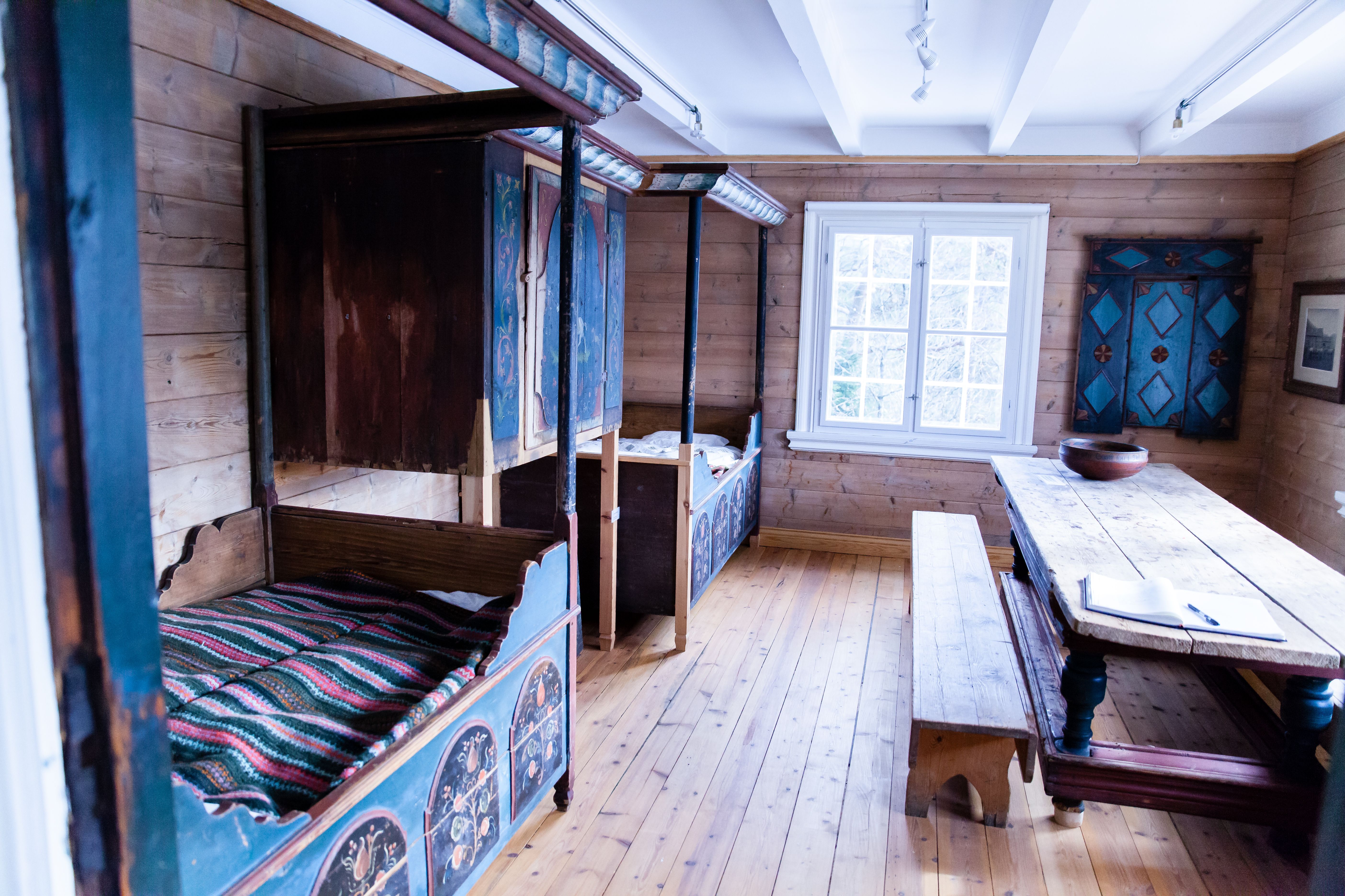 Marnardal Museum og Mjålandsstova, to senger med overskap midt i. Malt i blått med detaljer. Stort bord med benker vedsiden av