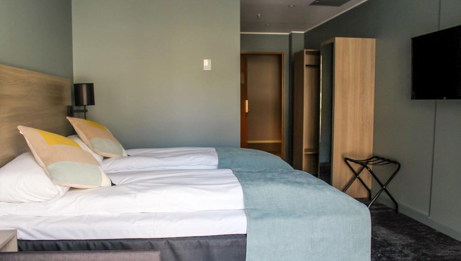 Standard hotellrom med enkeltsenger, TV og praktisk oppbevaring.