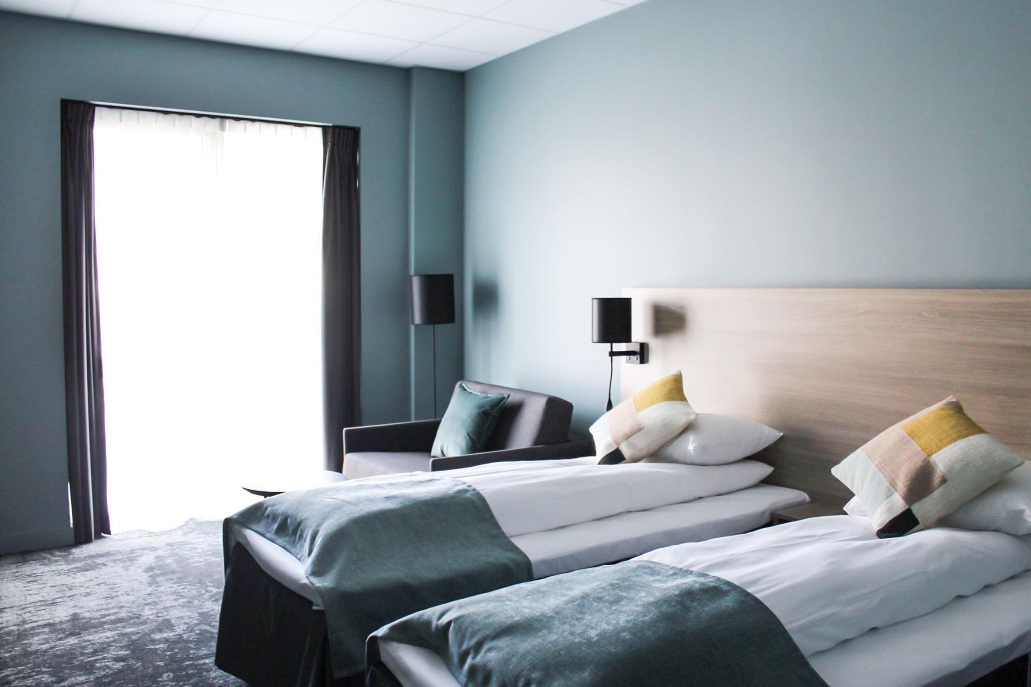 Lyst hotellrom med to enkeltsenger og moderne innreiing.