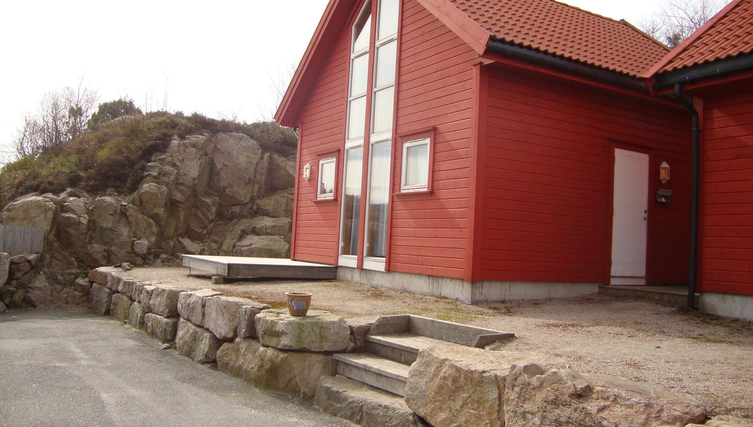 Rød hytte med steinplatting foran