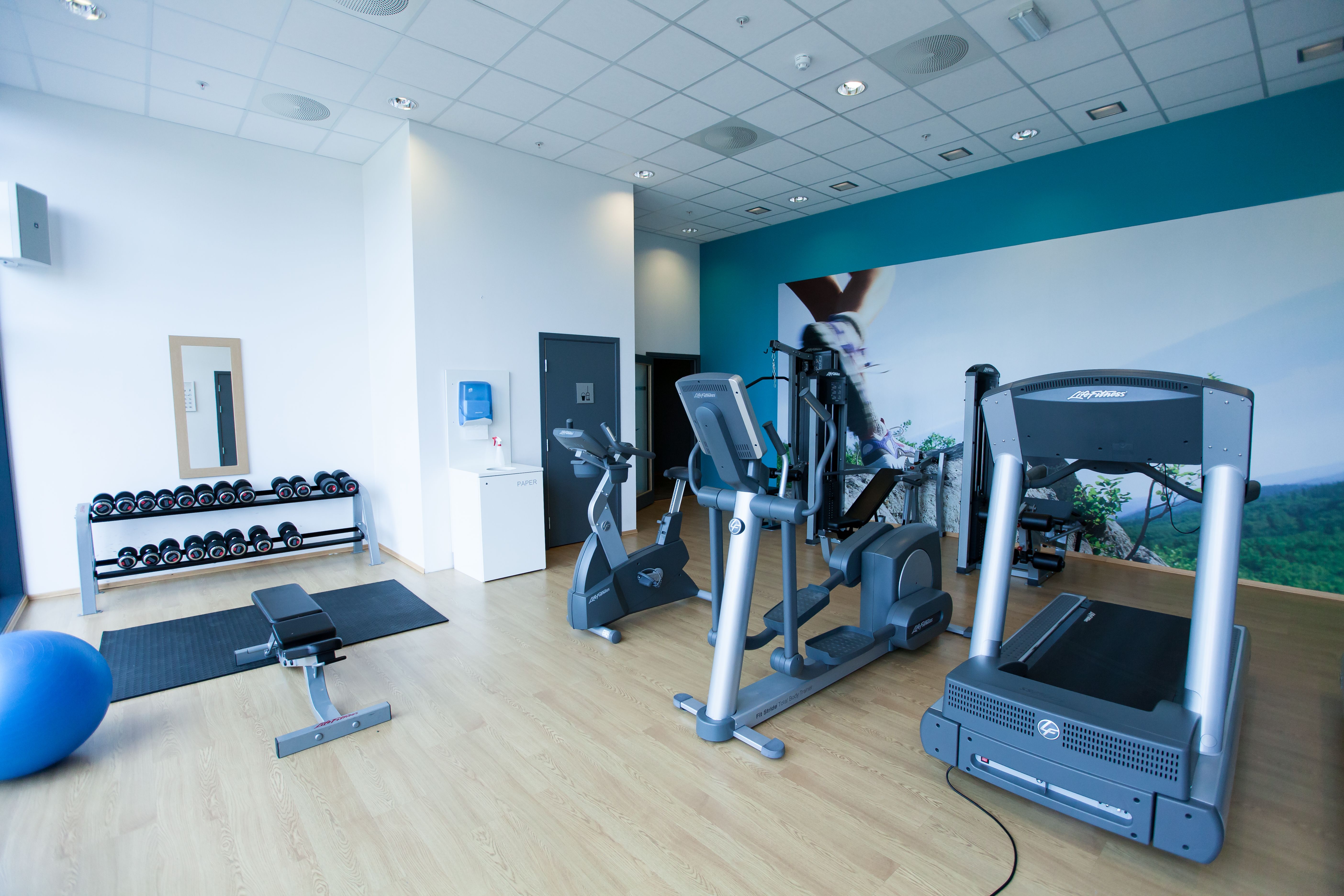 Lindesnes Havhotell – Fitness room with dumbbells and bench, exercise bike, elliptical machine, and treadmill.