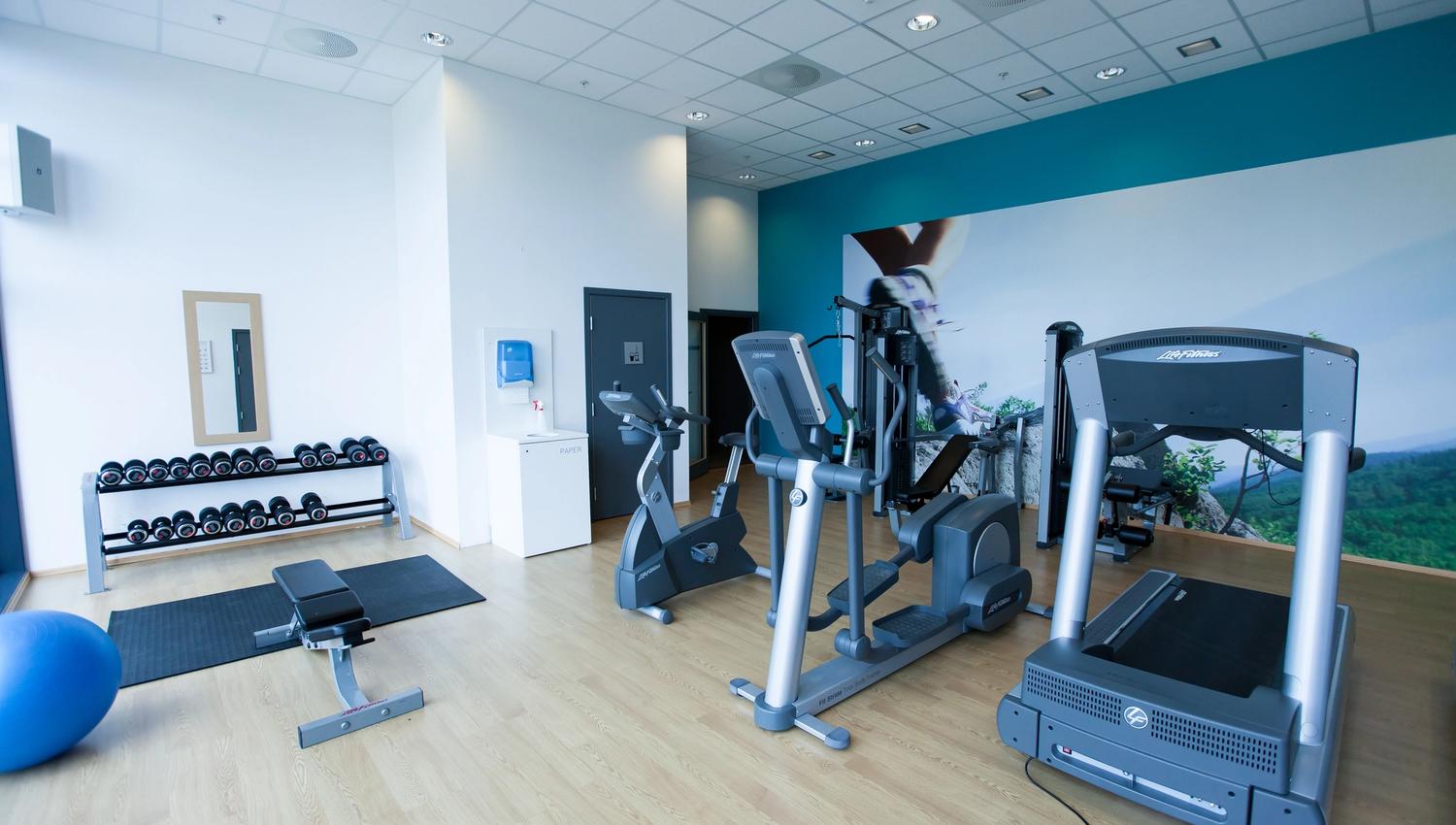 Lindesnes Havhotell – Fitness room with dumbbells and bench, exercise bike, elliptical machine, and treadmill.