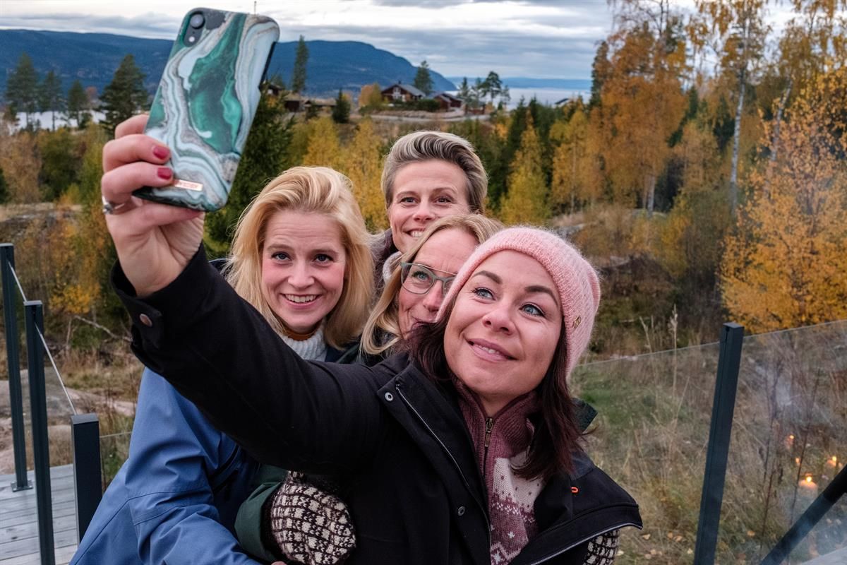 Personer tar en selfie i et skogsområde med høstfarger.