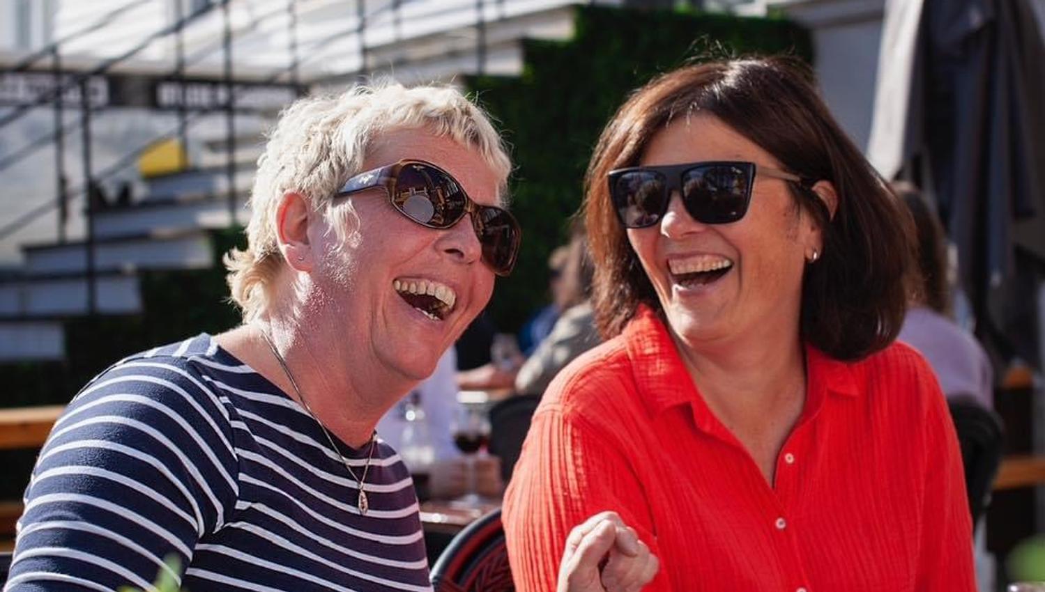 Smilende gjester som koser seg på uteservering