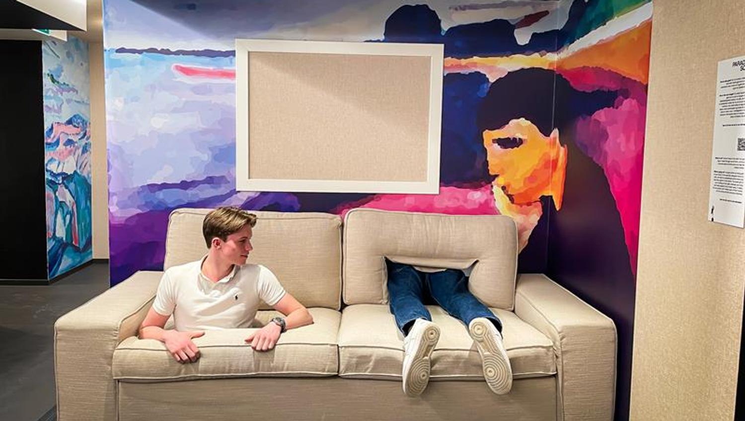 Beige sofa med en gutt som stikker ut gjennom et hull i setet, med et par bein som stikker ut ved siden av han.